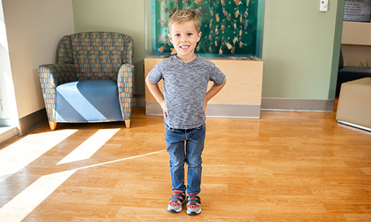 young boy smiling and posing standing tall for photo